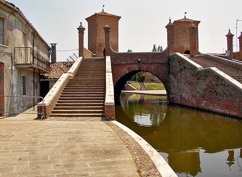 percorso pedonale che fiancheggia un canale e conduce a un ponte; la pavimentazione del ciglio  segnalata per non vedenti e ipovedenti